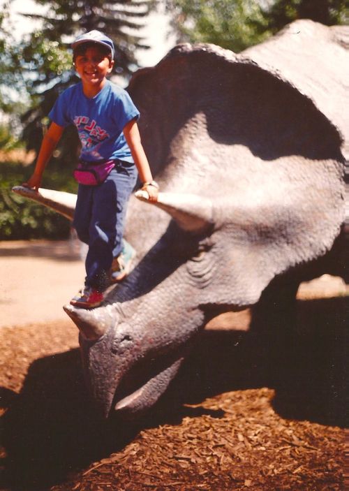 Kiron standing on a dinosaur sculpture