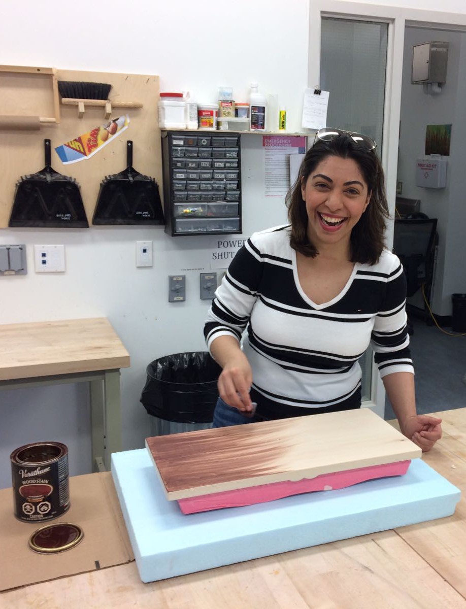 a student applying stain to a wooden photo album