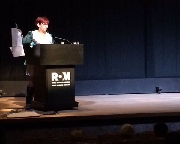 A Woman with red hair stands behind a podium