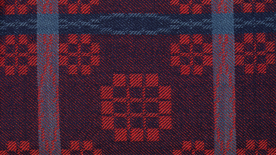 Detail of woven coverlet in red and blue.