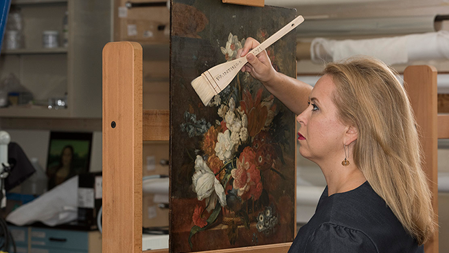 Portrait of a woman conservator working on a floral painting.