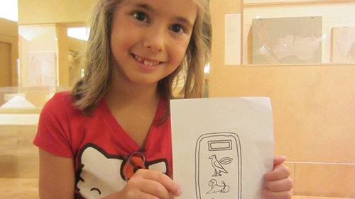 A girl holds a drawing of Egyptian Heiroglyphs