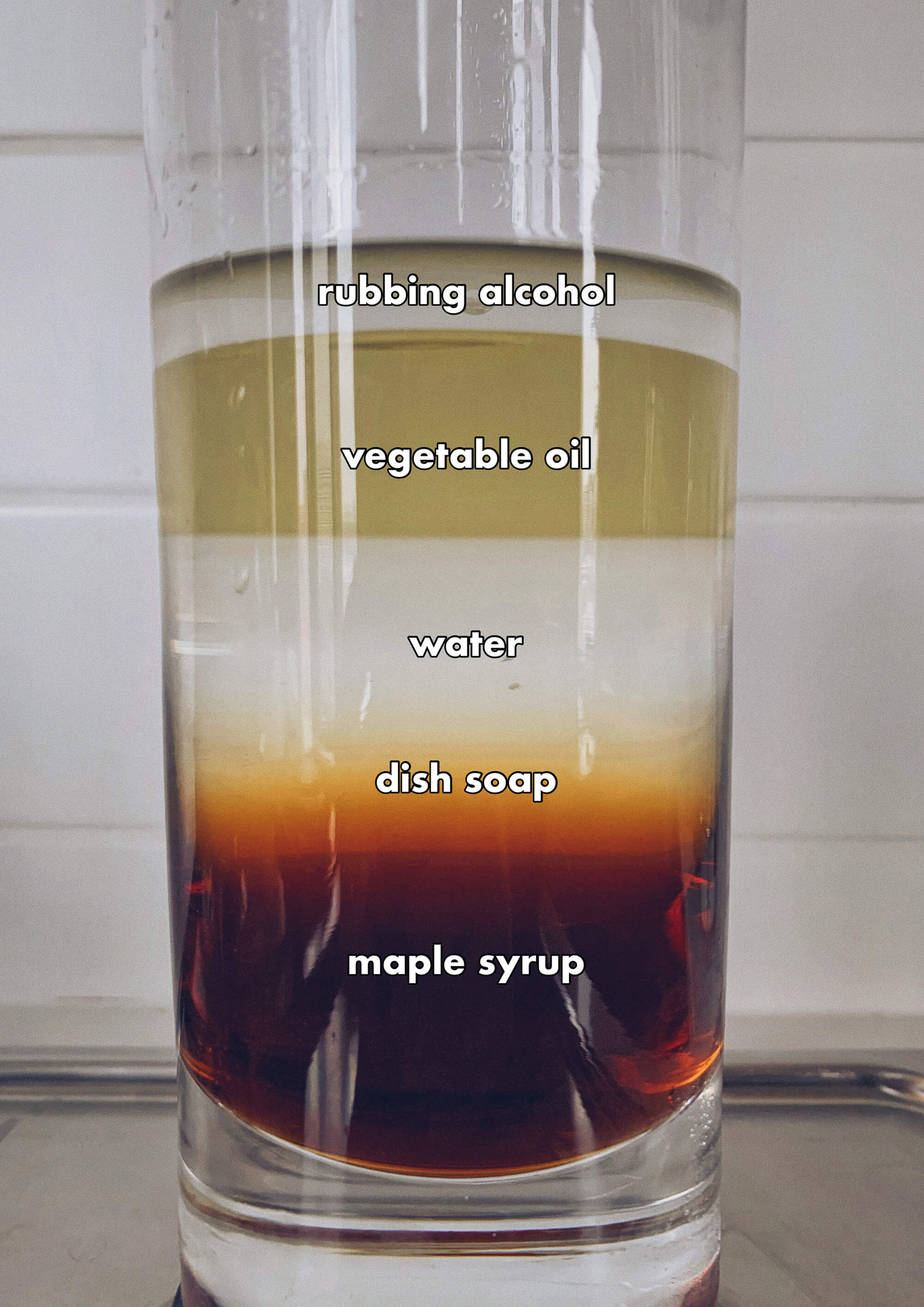 Rubbing alcohol, vegetable oil, water, dish soap, and maple syrup layered in a glass.