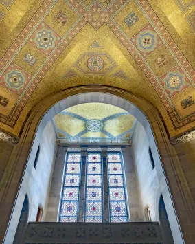 the ceiling of the ROM Rotunda the gold tiles shimmer in the light coming through the stain glass window.