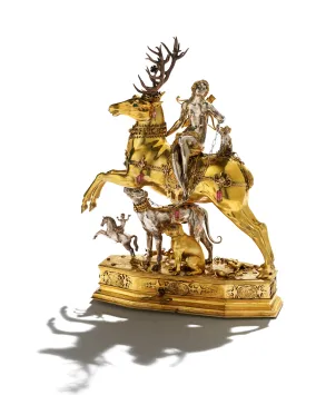 A silver woman sits on top of a golden stag, below her are dogs and another person riding a horse.