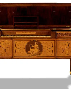 An ornate, antique wooden piano with decorative inlays, gold accents, and an image of a seated woman playing a lyre on the front panel, displayed against a white background.