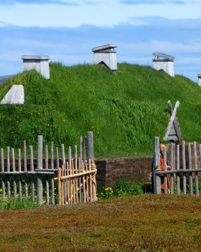 A dwelling with a grass-topped roof, surrounded by a fence.