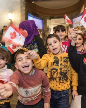 group of happy children waving Canadian flags