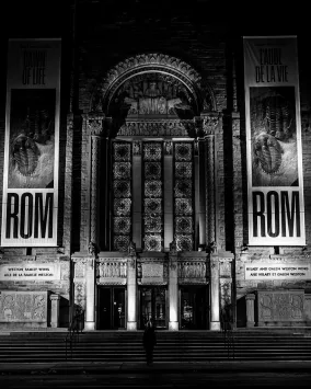 Black-and-white view of the ROM’s ornate entrance illuminated at night.