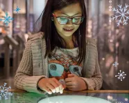 A girl stares down and smiles in wonder as she interacts with a screen in the Museum.
