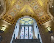 The ceiling of the ROM Rotunda the gold tiles shimmer in the light coming through the stain glass window.