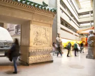 People walk through a gallery with a large entry gate