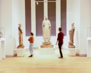 Two people look at three large Chinese sculptures.