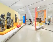 People walk around a gallery featuring statues of South Asian religious figures.