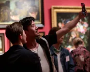 Patrons taking a selfie at an exhibition opening