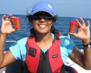 Asha de Vos, P.h.D. holds two bottles of freshly collected blue whale poop off the coast of Sri Lanka. Photo Credit: Oceanswell

