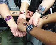 Six students show off their tattoo designs on their arms
