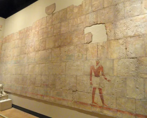 Mur d'un temple partiellement vandalisé représentant le voyage de la reine Hatchepsout à Pount. Un petit sphinx représentant le visage d'Hatchepsout se trouve dans le coin inférieur gauche.