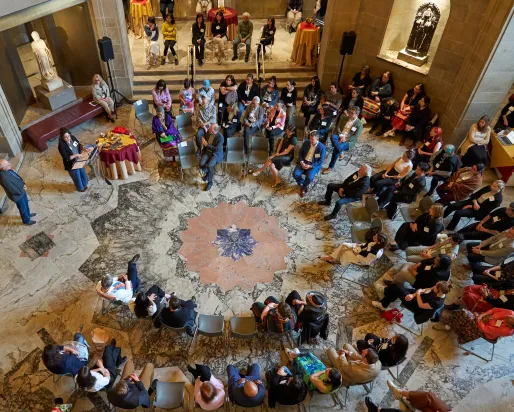 Presentation attendees in a large circle listening to a presentation.