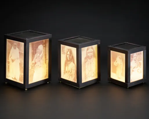 Three illuminated rectangular lanterns with images on the glass.