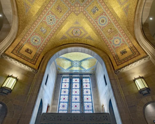 The ceiling of the ROM Rotunda the gold tiles shimmer in the light coming through the stain glass window.