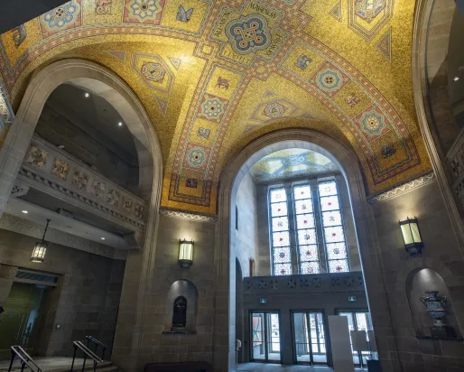 The ceiling of the ROM Rotunda the gold tiles shimmer in the light coming through the stain glass window.