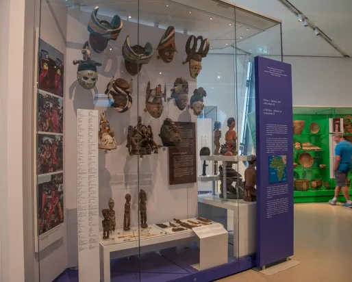 Un homme regarde un objet dans une boîte verte, au premier plan on peut voir des masques.