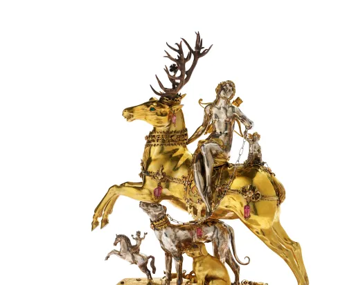 Une femme argentée est assise sur un cerf doré, en dessous d'elle se trouvent des chiens et une autre personne à cheval.