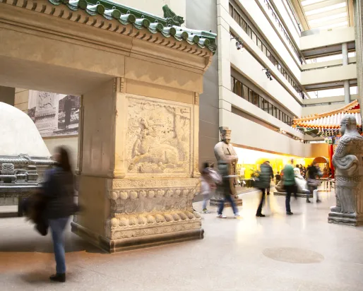 People walk through a gallery with a large entry gate