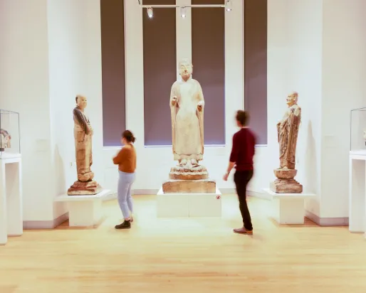 Two people look at three large Chinese sculptures.