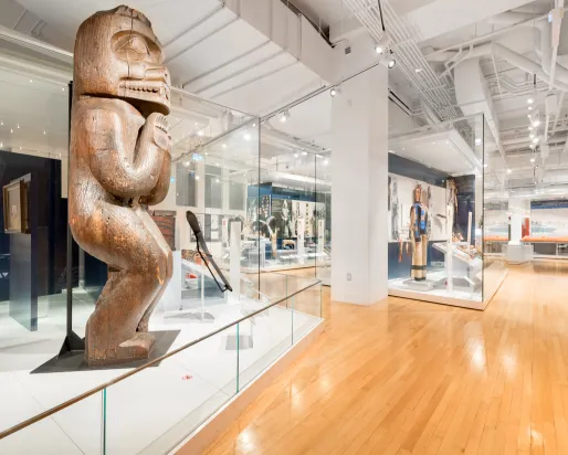 A gallery with a large carved wooden house post in the foreground