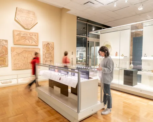 A person pauses to examine an object in a case.
