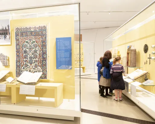 A family examines a Middle Eastern artifact in a gallery case.