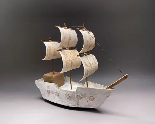 Full First Wave A detailed model of a ship with sails displayed against a neutral gray background, showcasing its intricate design.