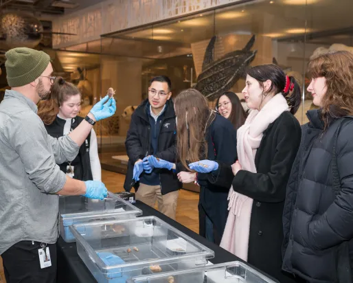 A group of ROM Members around a table with instuctor holding a specimen