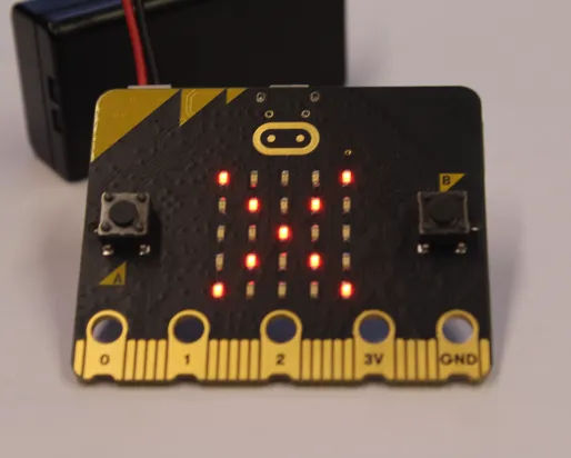 A black MicroBit displays illuminated LEDs in the form of an X