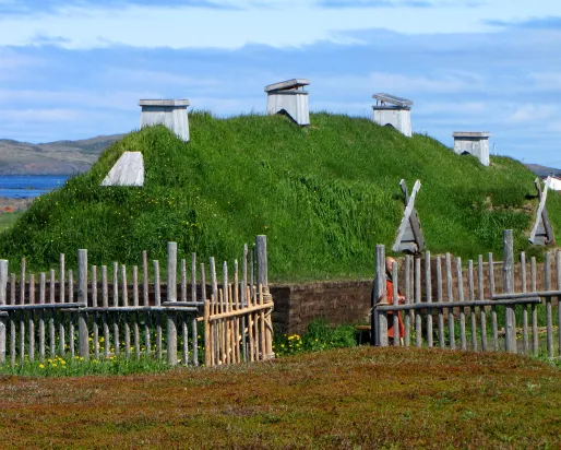 A dwelling with a grass-topped roof, surrounded by a fence.