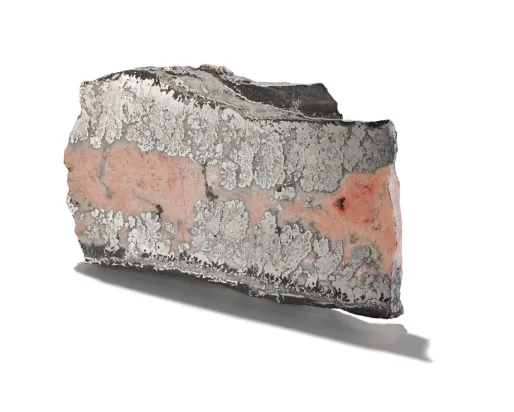 Pie-shaped sample of cobalt mineral encased in smaltite, shown on a white background.