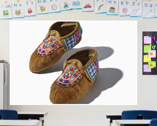 A screen in a colourful classroom displays a pair of beaded leather moccasins