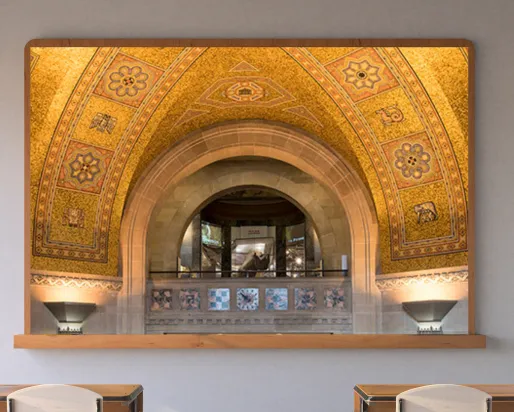 A screen in a classroom displays a balcony with an arched roof beneath a golden mosaic ceiling. A rhinoceros in a case is visible through the arch.