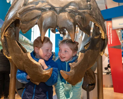 Two children look out from the mouth of the Dunkleosteus in the Dawn of Life Gallery