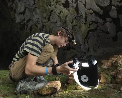 Beckett Robertson, deep inside a cave in the Dominican Republic, where he captured his award-winning photo of a whip spider. (2023)