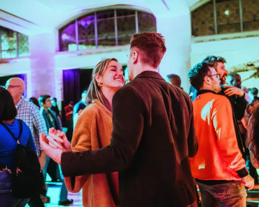 Couple locking hands in a crowd at a museum.
