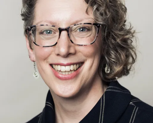 A woman with curly brown hair wearing glasses