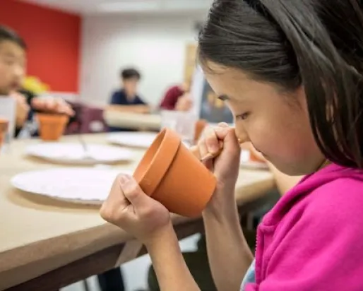 Student in the ROM Makerspace drawing with pencil on a clay pot
