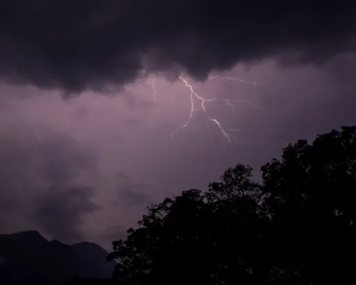 Un éclair traverse un ciel violet au-dessus des montagnes et des forêts tropicales du Sri Lanka.
