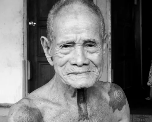 Photographie en noir et blanc d'un homme âgé avec des tatouages sur le cou et les épaules
