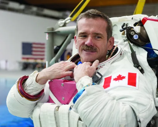 A photograph of a man in an astronaut suit without a helmet
