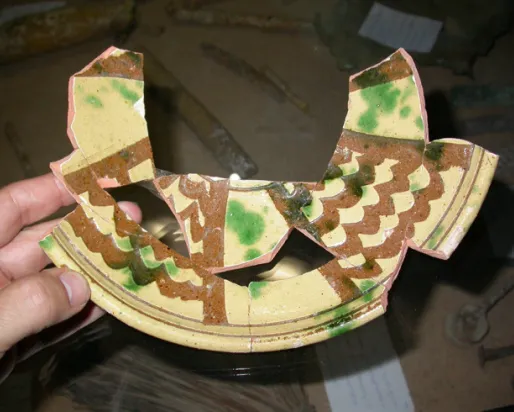 Poterie à corps en terre cuite, engobe blanc, incision de l'engobe à l'aide d'un outil large, glaçure plombifère, éclaboussée de vert de cuivre, probablement milieu du XIVe siècle.
