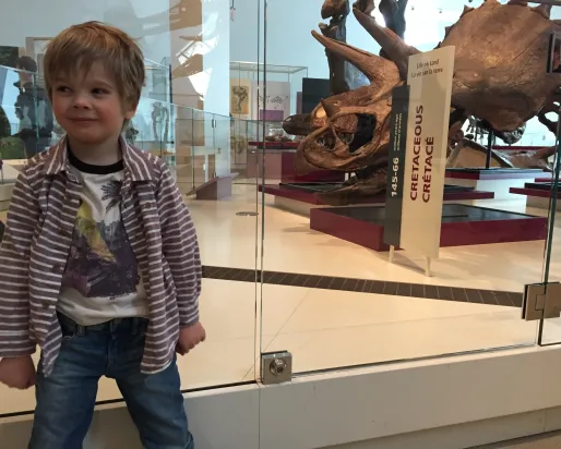 Theo stands next to a Triceratops skull in the Royal Ontario Museum's dinosaur gallery
